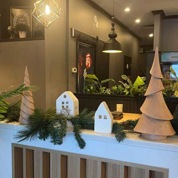 Cozy restaurant counter decorated with wooden trees, house figurines, and pine garlands