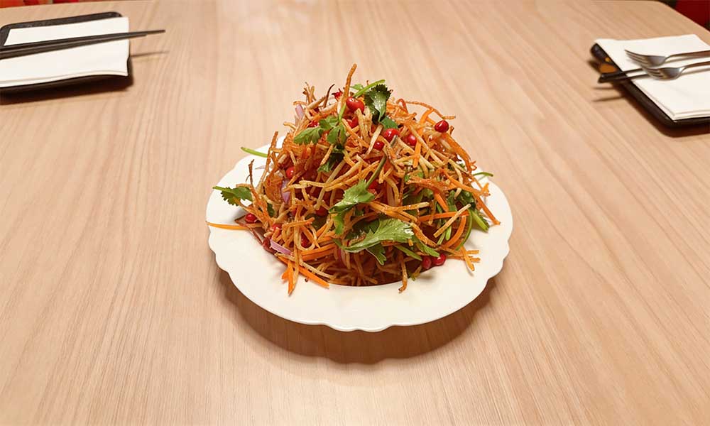 Crispy shredded vegetable salad with peanuts, cilantro, and carrot on scalloped plate